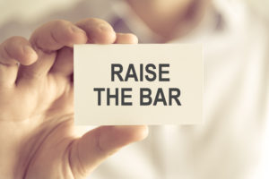 Businessman holding RAISE THE BAR message card